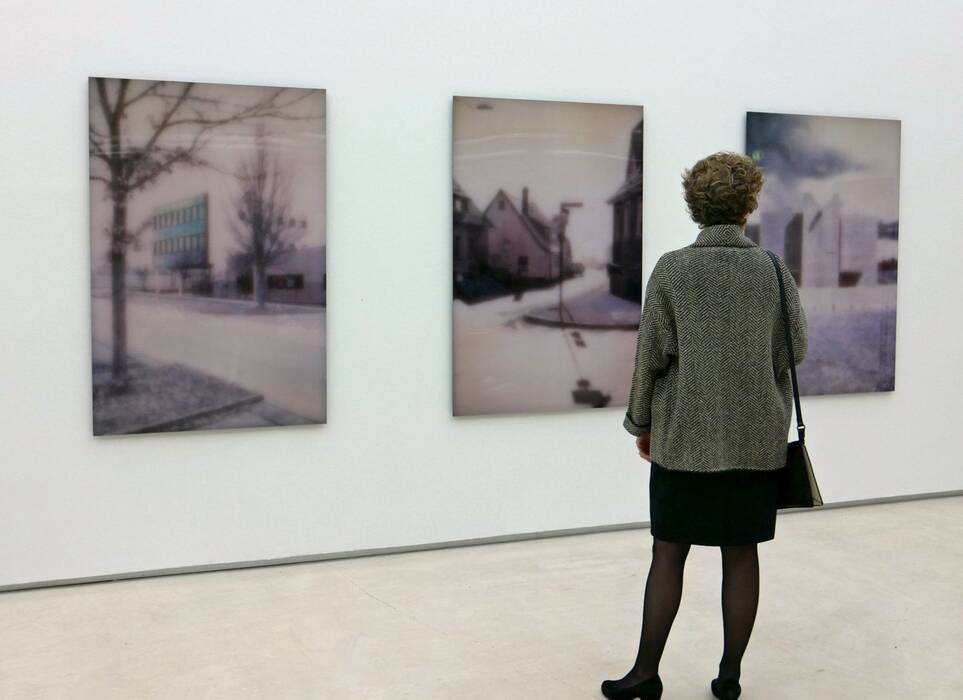 Eine Frau betrachtet eine Wachsarbeitserie mit urbanem Motiv. Ausstellung "Blickrichtungen" von Gert Wiedmaier, 2017.