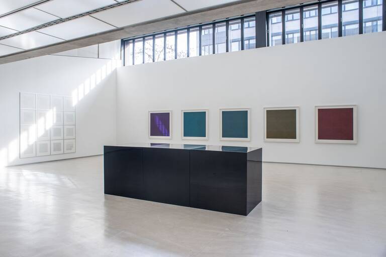 Ausstellung Sol LeWItt: Im Vordergrund das Werk Black Cubes, drei schwarze Quader (100 x 300 x 100 cm), Emaille auf Fiberglas, im Hintergrund fünf gerahmte Siebdruck-Blätter (118 x 118 cm) in rot, olive, blau, grün und aubergine aus dem Besitz der Stadt Ostfildern. An der linken Wand 16 schwarz-weiße Lithografien (Lines Of One Inch In Four Directions Ánd All Combinations) von Sol LeWitt in hellen, quadratischen Rahmen