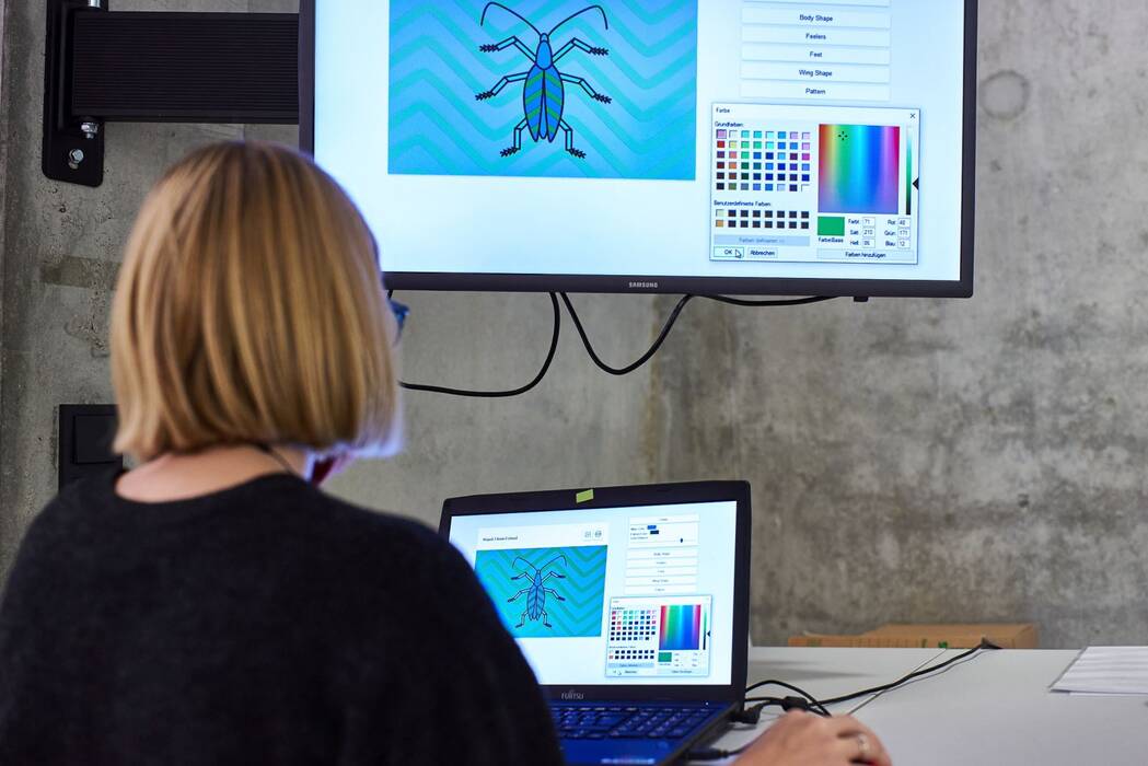 Bleeptrack "Beetlesbot" von Sabine Wieluch. Eine Ausstellungsbesucherin sitzt vor Laptop.