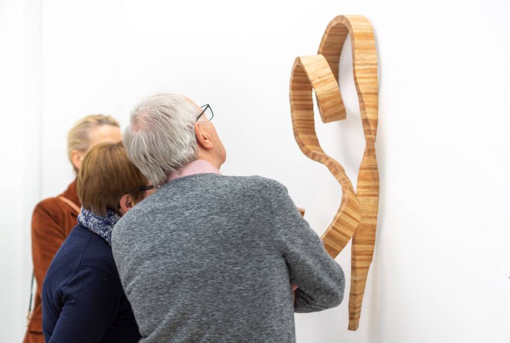 Ausstellungsbesucher vor einer Wandskulptur von Robert Steng, "Brettspiele", 2020.