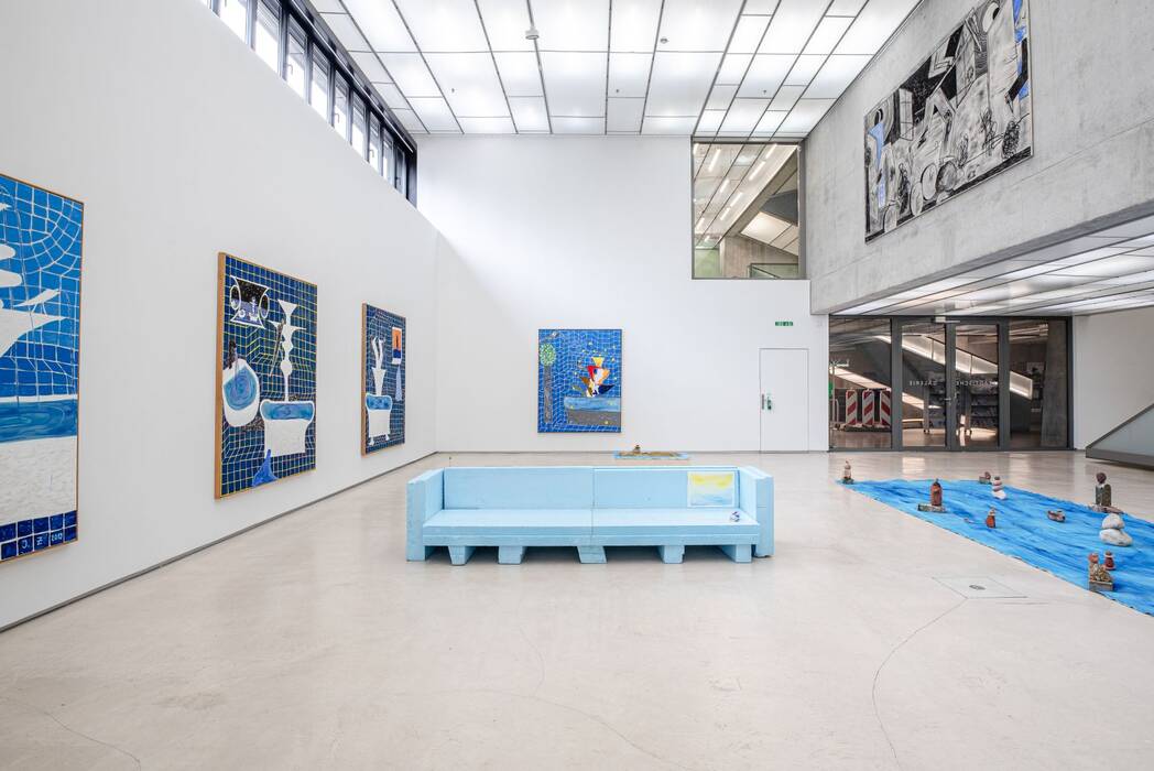 Künstler: Jan Zöller. Raumansicht. Mittig ein hellblaues Sofaobjekt. Eine Bodenarbeit, die wie ein Fluss wirkt. An den Wänden hängen Malereien in Blautönen.