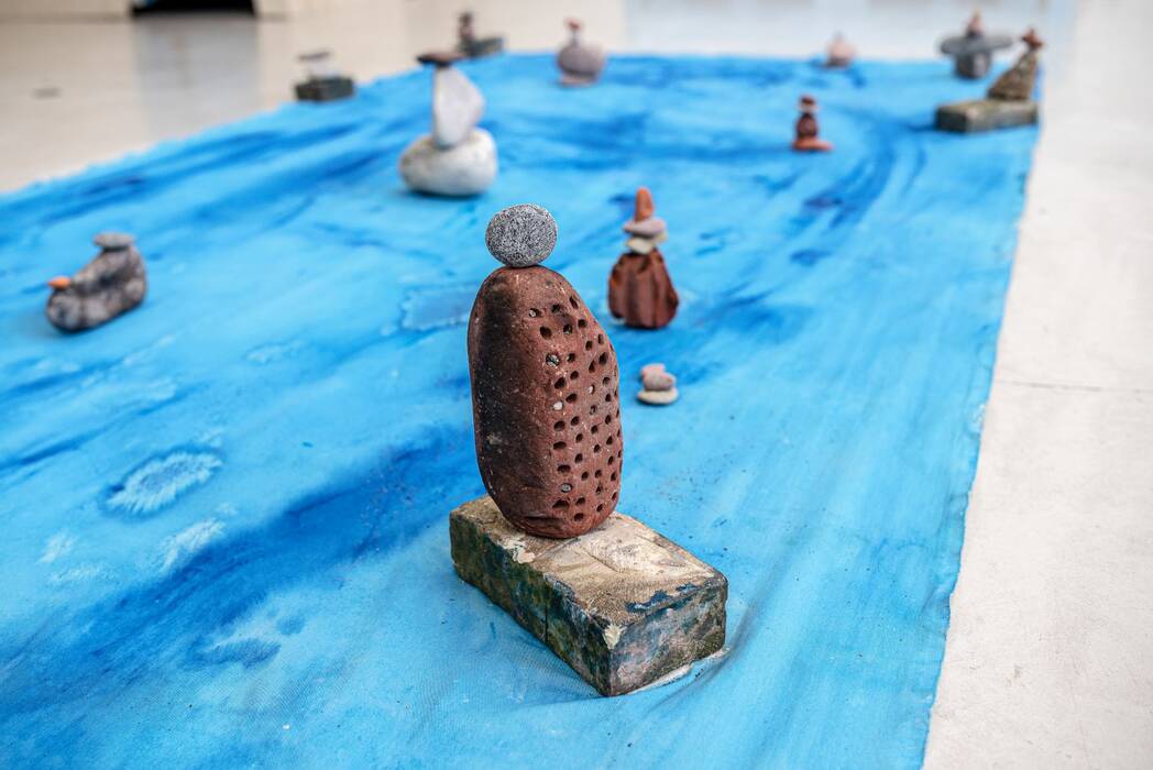 Eine blaue Plane liegt auf dem Boden. Obenauf gestapelte Steine und andere Gebilde. Jan Zöller, "keine Zeit zum Baden".