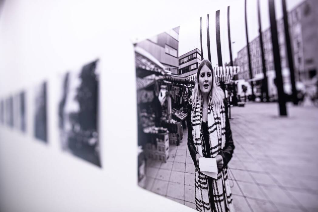 Schwarzweiß Fotografie einer Performance auf dem Markt vor dem Stadthaus. Ausstellung "Thinking About Video Art - Kunst am Wegesrand" von Anette C. Halm.