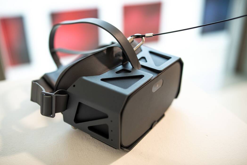 Vordergrund: Eine schwarze VR - Brille. Hintergrund: Blick in den Galerieraum. Ausstellung "Thinking About Video Art - Kunst am Wegesrand" von Anette C. Halm
