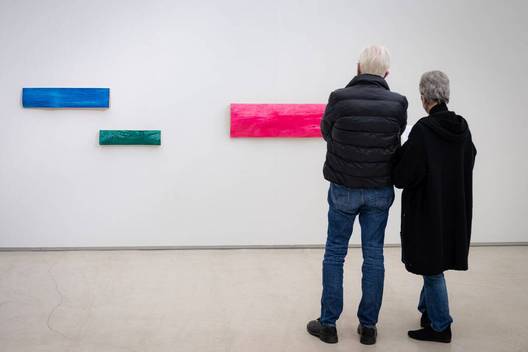 Wandarbeiten von Günther Holder. Ausstellungsbesucher vor drei farbigen Balken an der Wand. 