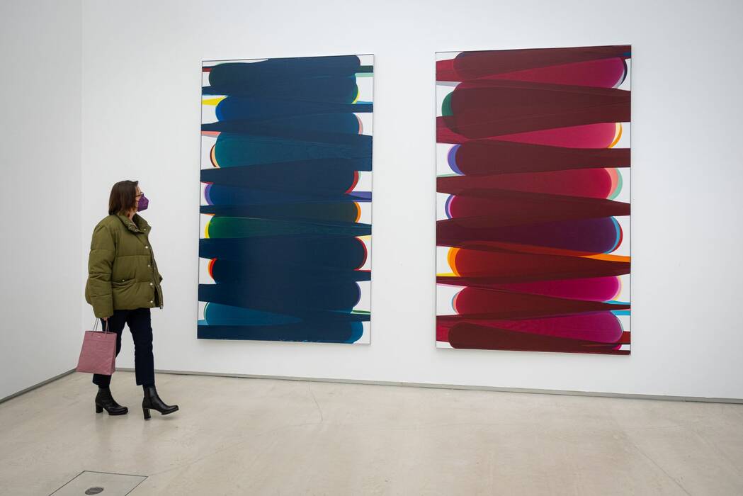 "Pouring on Canvas - Purple, Blue" von Rainer Splitt. Eine Besucherin betrachtet die Leinwände.