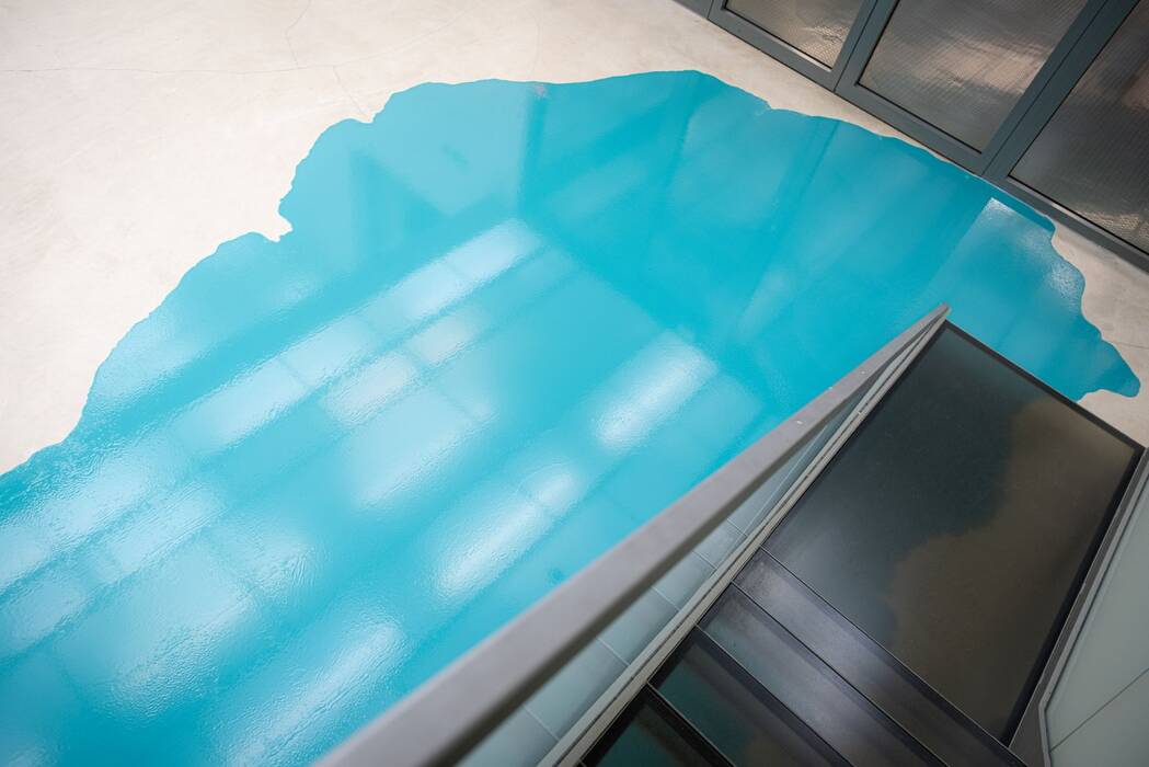Farbguss, 2022 von Rainer Splitt. Die Treppe mündet in einem türkisfarbenen Farbfleck auf dem Boden.