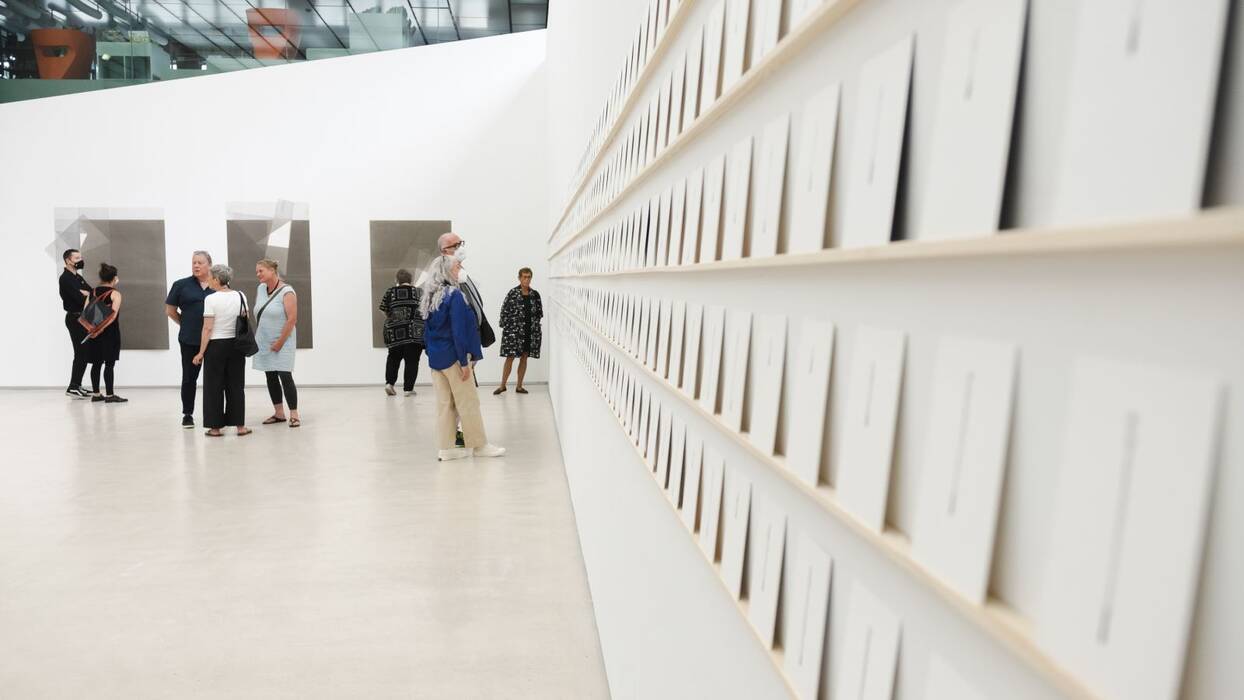 Instagram Projekt "Daily Lines", 2021 von Michelin Kober. Vier scheinbar endlose Passepartoutskarton-Reihen (je 15x10cm) sind entlang der Wand aufgereiht. Vor Kopf stehen die Ausstellungsbesucher vor großformatigen Tuschezeichnungen.