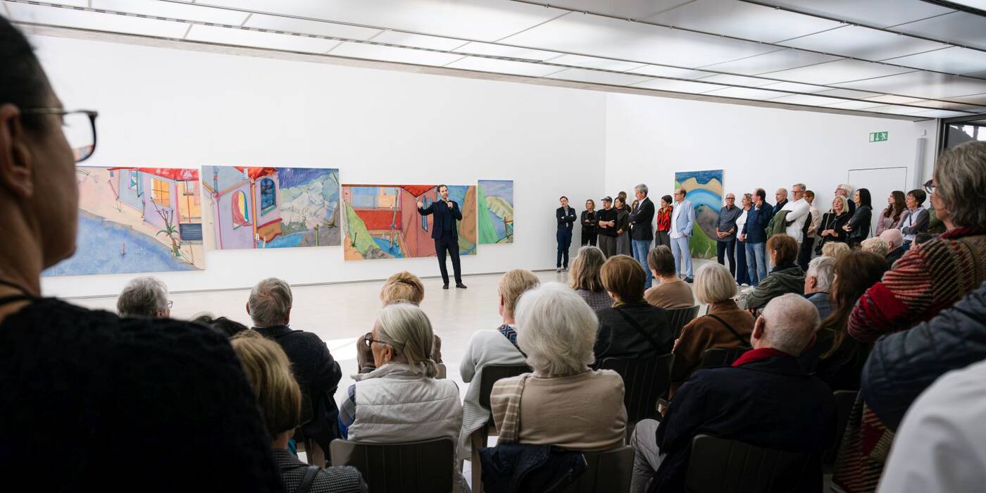 Redner Hendrik Bündge, Kurator der Staatsgalerie, vor dem Publikum der Vernissage.