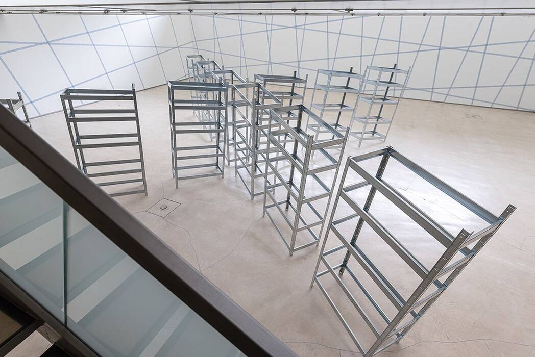 Schwerlastregal - Installation, in der die Regale drohen zu kippen. Die Wände sind mit hellblauem Klebeband gerastert.
