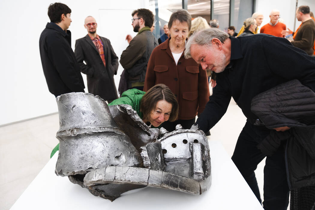 Besucherinnen betrachten das Werk "Kollision", 2025 von Erik Sturm. Es handelt sich um ein Fundobjekt, Stuttgart 21 Baustelle Bohrkopf und Stahlträger Fragmente Stahl  einen Bohrkopf von Erik Sturm