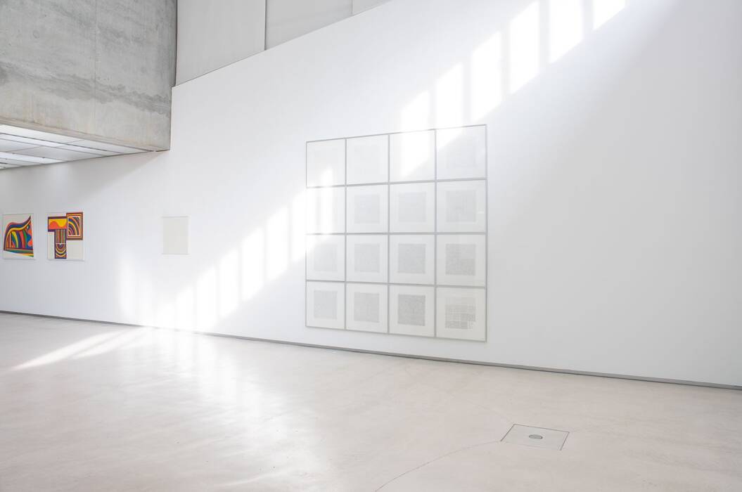 Eine Wand der Galerie mit 16 schwarz-weißen Lithografien (Lines Of One Inch In Four Directions Ánd All Combinations) von Sol LeWitt in hellen, quadratischen Rahmen