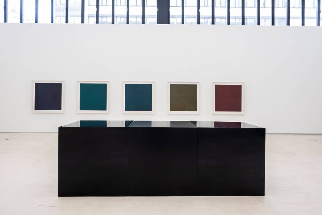 Ausstellung Sol LeWitt: Im Vordergrund das Werk Black Cubes, drei schwarze Quader (100 x 300 x 100 cm), Emaille auf Fiberglas, im Hintergrund fünf gerahmte Siebdruck-Blätter (118 x 118 cm) in rot, olive, blau, grün und aubergine aus dem Besitz der Stadt Ostfildern